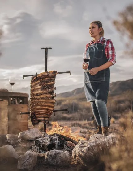 Una mujer en la montaña cocinando carne