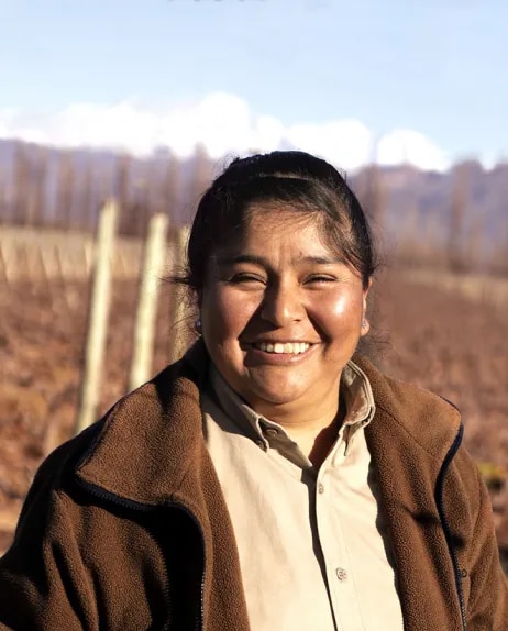 A woman standing in front of high altitude Malbec vineyards in Mendoza