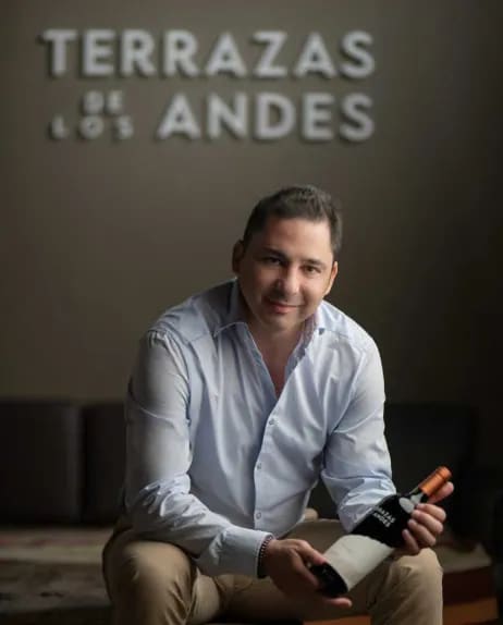 Un hombre sentado con una botella de vino tinto Malbec de Mendoza en Terrazas de los Andes
